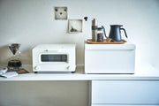 Minimalist counter featuring Yamazaki Home | Tower Bread Box, Steel, Black, beside a toaster-oven, Chemex, coffee grinder set, emphasizing sleek kitchen organization.