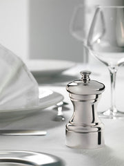 Peugeot Mignonnette Silver Plated Salt Mill, 4 inches, elegantly placed on a refined dining table with white dinnerware, cutlery, and wine glasses, highlighting its sophisticated design.