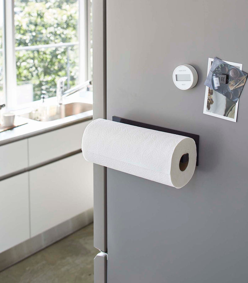 Yamazaki Home Magnetic Steel Paper Towel Holder, White, magnetically attached to a gray fridge in a modern kitchen, holds a fresh paper towel roll.