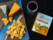 Southern Straws Cheese Straws arranged with cheddar, blue cheese, crackers, and red wine on a wooden board, showcasing a classic Southern snack spread from Athens Cooks.