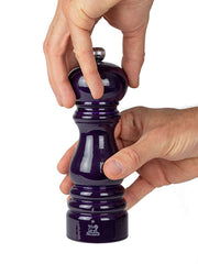 Peugeot | Paris u'Select Wooden Pepper Mill, 7 Inches, in hand while twisting the top to grind, showcasing its ergonomic design and aubergine purple lacquer finish.