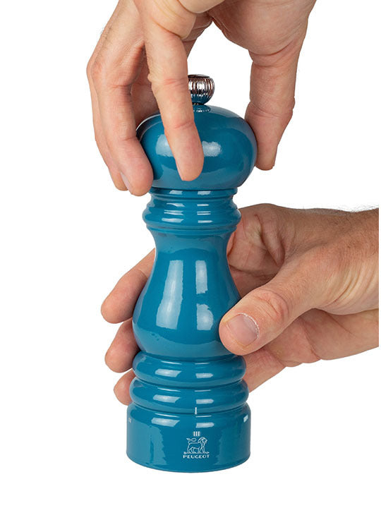 Peugeot | Paris u'Select Pacific Blue Lacquered Pepper Mill, 7 inches, being twisted by hands, showcasing its ergonomic design and precision grinding mechanism.