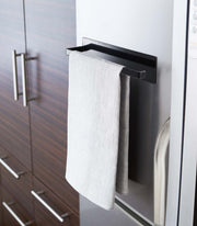 Yamazaki Home Magnetic Steel Paper Towel Holder in white, mounted on a fridge, holding a gray towel, exemplifying minimalist kitchen organization.