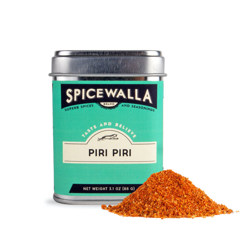 Spicewalla | Piri Piri seasoning tin with a mound of reddish-orange spice blend, offering a bittersweet and spicy flavor ideal for Portuguese dishes and roasted chicken.