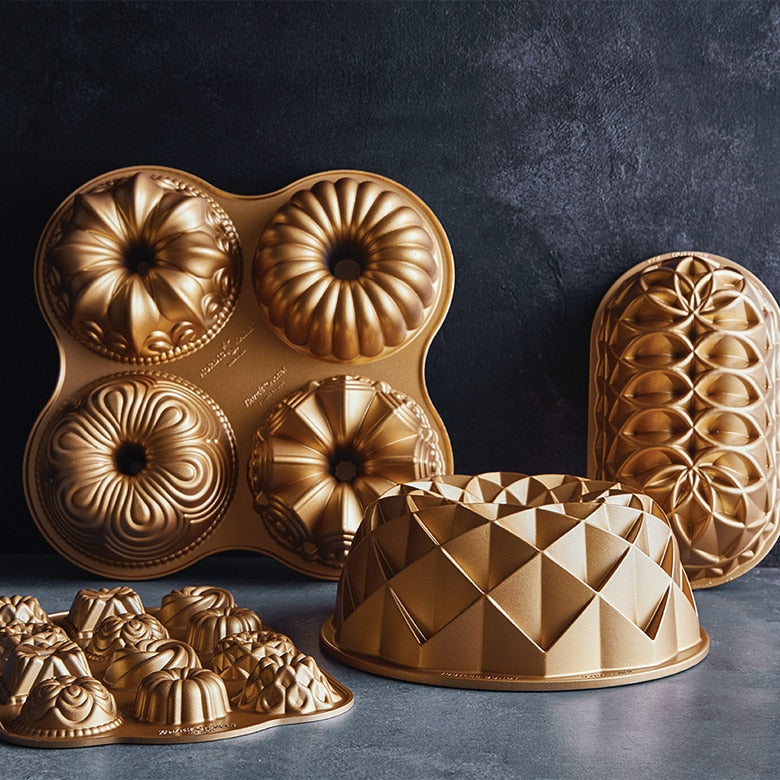 Nordic Ware | Mini Bundt Charms Pan featuring six intricate Bundt shapes for versatile baking, ideal for cakes, brownies, and more, showcased in gold molds.