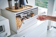 Yamazaki Home | Tower Bread Box, Steel, Black, shown open with bread and condiments inside, topped with coffee accessories, enhancing kitchen organization and style.