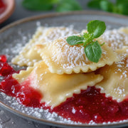 Marcato Ravioli Tablet - Green assists in creating dessert ravioli, shown dusted with sugar on berry coulis, garnished with fresh herbs, embodying culinary precision.