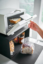 Yamazaki Home | Tower Bread Box, Steel, Black, displayed with bread and jams, enhances kitchen organization and decor in a stylish, compact design.