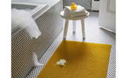 Chilewich Solid Shag Mat in Cactus, 24x36, displayed on tiled bathroom floor with yellow accents, highlighting its modern design and durability.