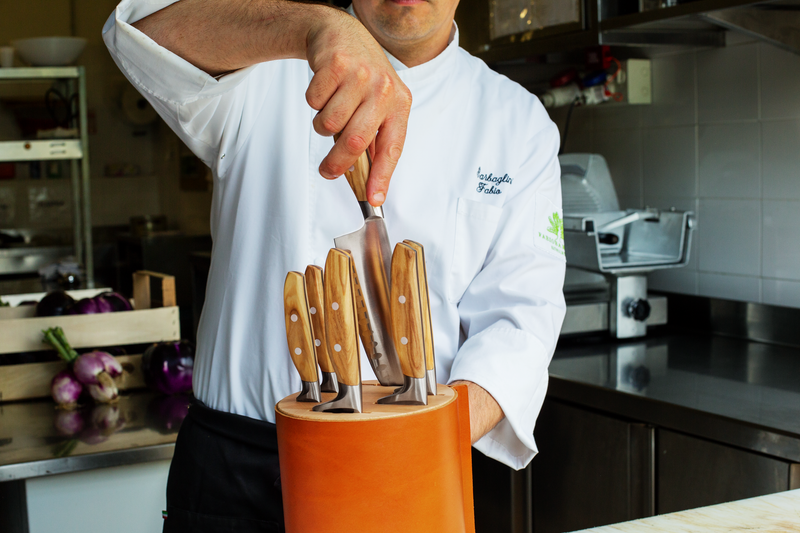 Man holding a Wüsthof 6-Slot Block in Beech with Leather, featuring a set of knives, highlighting kitchen tool essentials from Athens Cooks.