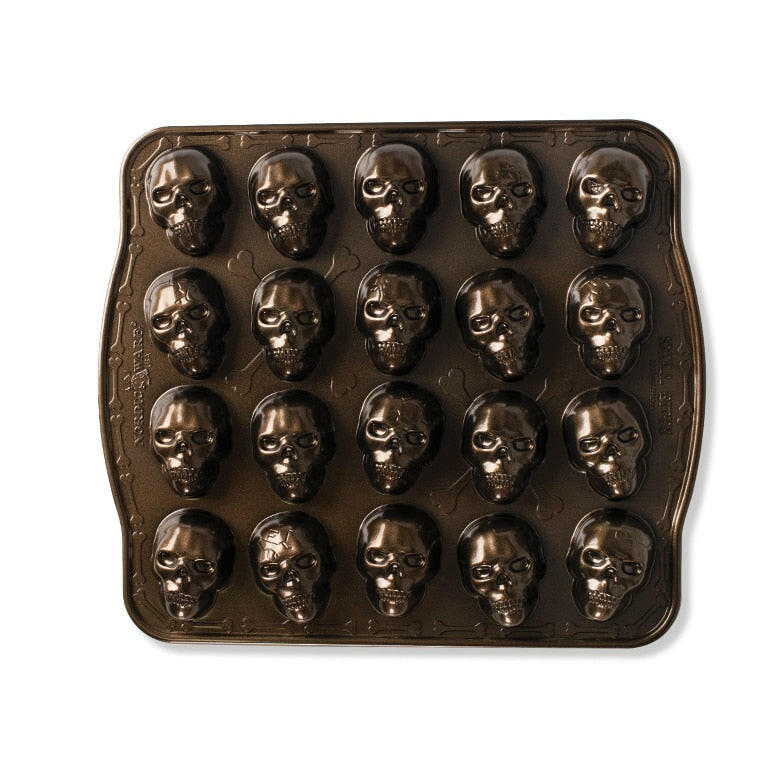 Nordic Ware | Skull Cakelet Pans - Skull Bites: Dark non-stick pan with 20 skull-shaped cavities for creative treats like mini cakes or candies.