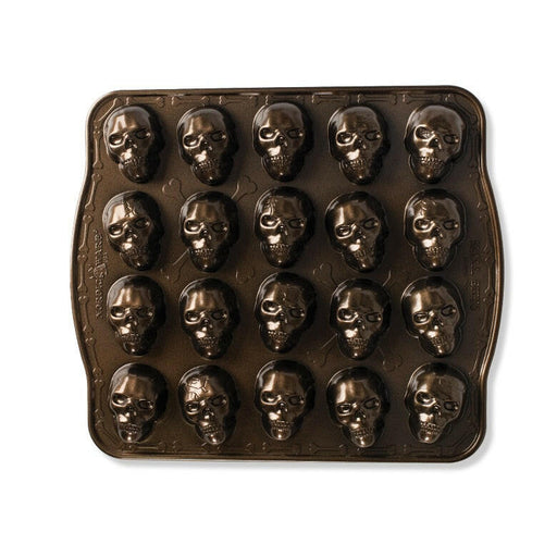 Nordic Ware | Skull Cakelet Pans - Skull Bites: Dark non-stick pan with 20 skull-shaped cavities for creative treats like mini cakes or candies.