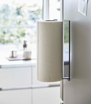 Yamazaki Home | Magnetic Steel Paper Towel Holder, White, elegantly mounted on a fridge, showcasing its minimalist design and space-saving functionality in a modern kitchen setting.