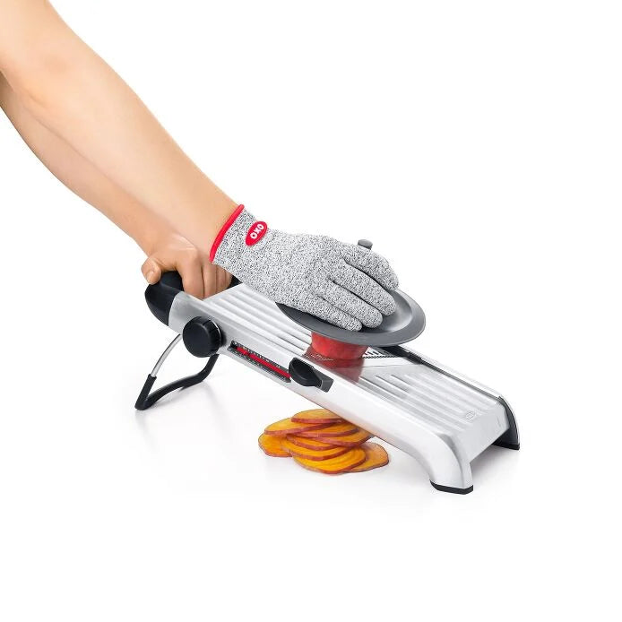 Hand using OXO Chef's Steel Mandoline to slice vegetables, showcasing its precision and efficiency, ideal for culinary enthusiasts from Athens Cooks.