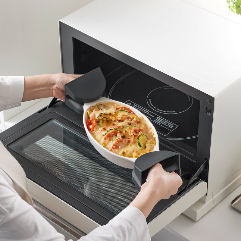 Removing a gratin-filled dish with Yamazaki Home Magnetic Pot Holders, Silicone, Black, highlighting their heat-resistant grip in a kitchen setting.
