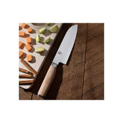 Shun Premier Blonde Santoku, 7, with a hammered-finish blade and blonde Pakkawood handle on a wooden table, beside diced vegetables and a wooden cutting board.