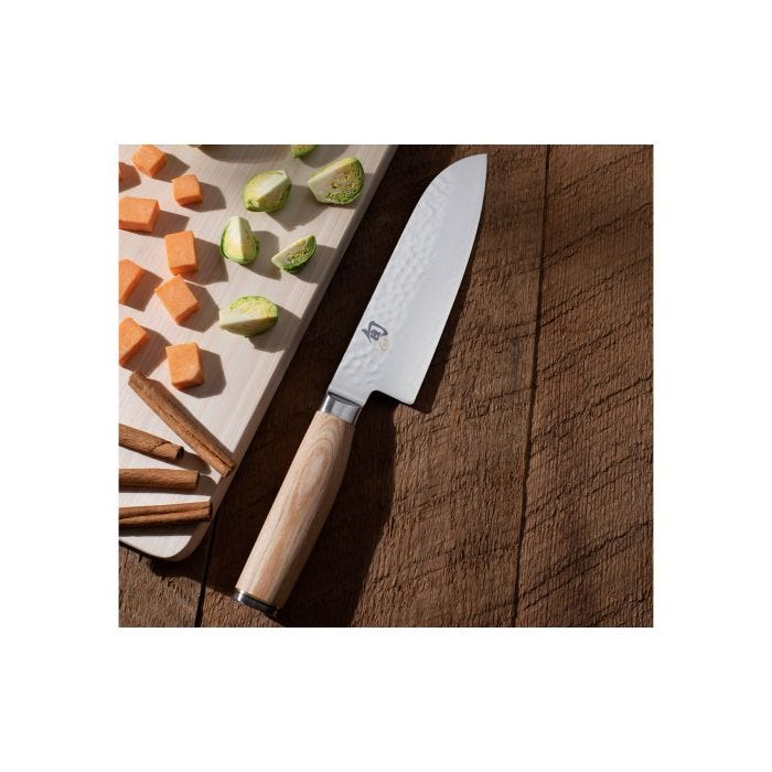 Shun Premier Blonde Santoku, 7, with a hammered-finish blade and blonde Pakkawood handle on a wooden table, beside diced vegetables and a wooden cutting board.