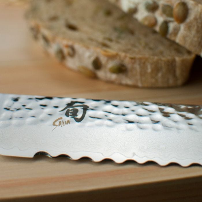 Shun | Premier Blonde Bread Knife, 9, serrated blade on a wooden board, perfectly slices seeded whole-grain bread without crushing, ideal for crusty or tender loaves.