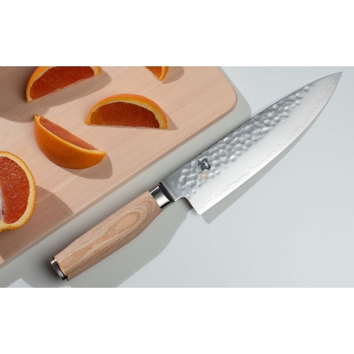 Shun | Premier Blonde Chef's Knife, 8 inches, with a hammered finish and light wooden handle, rests beside a cutting board with grapefruit wedges.