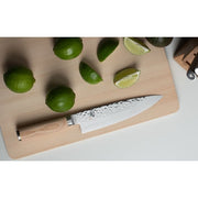 Shun | Premier Blonde Chef's Knife, 8 inches, displayed on a cutting board with limes, highlights its hammered blade and light wood handle, embodying precision and elegance.