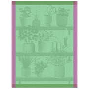 Le Jacquard Français | Herbes Fraiches Tea Towel, Green displayed with potted herbs and gardening tools on wooden shelves, emphasizing culinary and kitchen application.