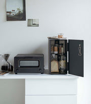 Yamazaki Home Bread Box in black steel on a minimalist countertop, keeping baked goods organized and fresh, with a nearby pour-over coffee setup and mini-oven.