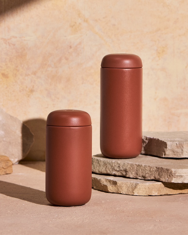 FELLOW | Carter Move Mug, Sienna / 16 oz: Two rust-colored, matte-finished travel mugs with rounded lids, designed to maintain drink flavor and temperature, ideal for on-the-go use.