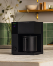 FELLOW | Aiden Precision Coffee Maker, Matte Black on countertop with mug, offering automated pour-over brewing for perfect coffee every time.