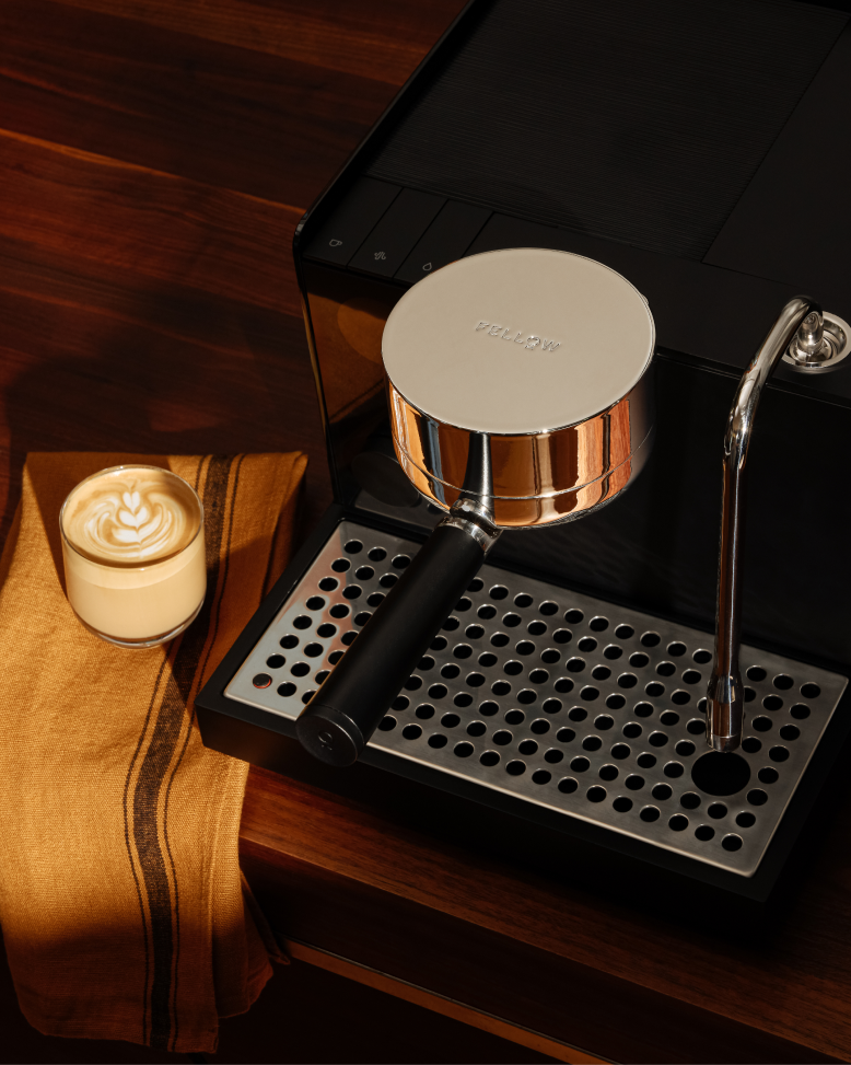 FELLOW | Espresso Series 1 machine, portafilter, and steam wand on a counter with latte in a glass cup, showcasing professional home espresso setup.