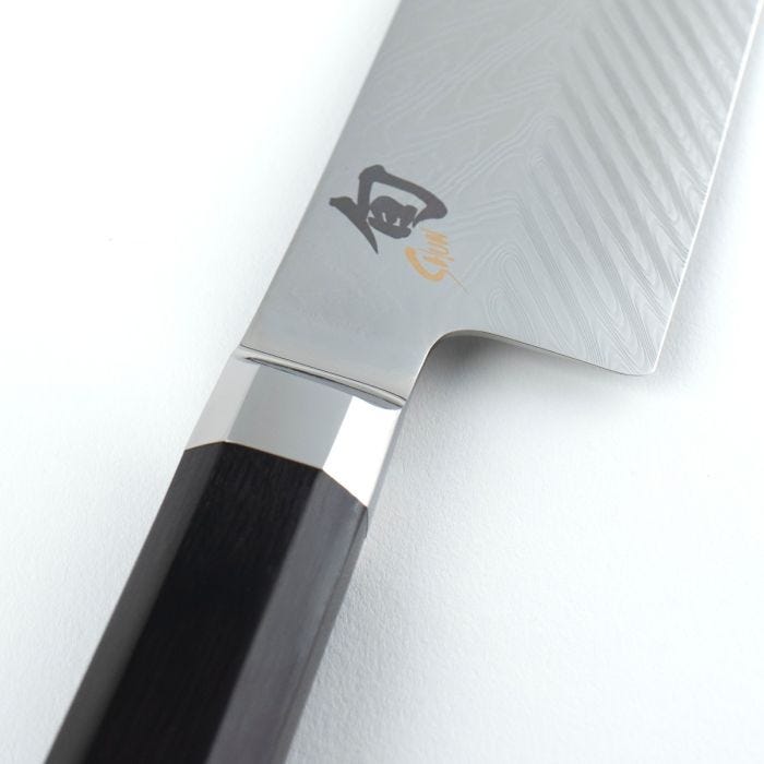 Close-up of Shun Dual Core Nakiri, 6.5 inches, showcasing its Damascus steel blade, polished bolster, and dark octagonal wooden handle, ideal for versatile kitchen use.