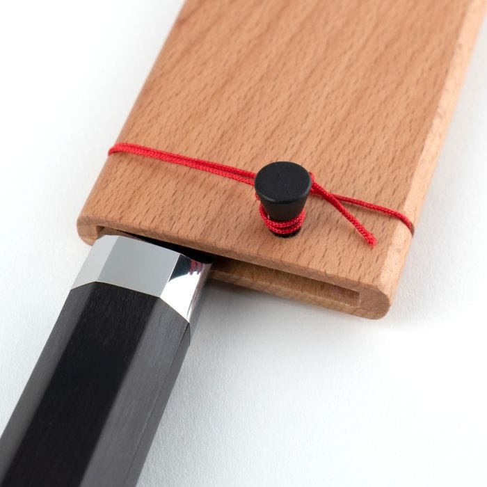 Japanese-style Dual Core Nakiri chisel handle in octagonal ebony PakkaWood, partially sheathed in beech saya with red cord, showcasing traditional craftsmanship and functionality.