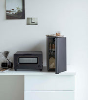 Yamazaki Home | Bread Box, Vertical, Steel, Black, keeping baked goods fresh, sits open revealing cookie jars, enhancing kitchen decor alongside a toaster-oven and coffee dripper.