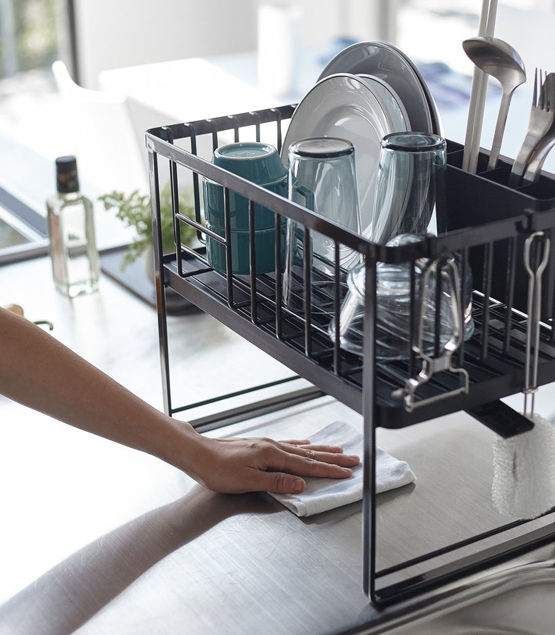 Yamazaki Home | Two-Tier Dish Rack, White, loaded with dishes, on a clean countertop. Draining spout and utensil holder visible, enhancing kitchen organization.