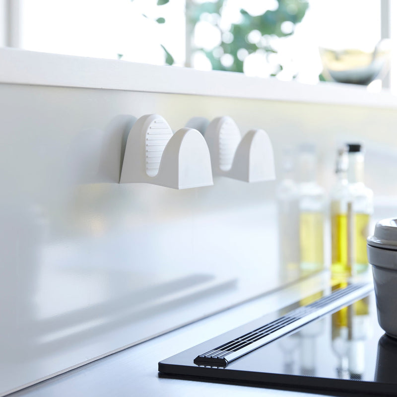 Yamazaki Home Magnetic Pot Holders, Silicone, Black, mounted on the backsplash, complement a modern kitchen setup with induction cooktop and culinary essentials.