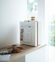 Yamazaki Home | Bread Box, Vertical, Steel + Wood on a light wood counter, with a recipe, timer, tea towel, and cookie jar on top.