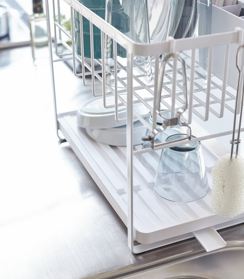 Yamazaki Home | Two-Tier Dish Rack, White: A space-saving, white metal rack with adjustable features, including a rotating spout and removable plastic tray, ideal for efficient dish drying.