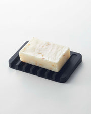 Yamazaki Home | Flow Self-Draining Soap Tray: Handmade soap on a silicone tray with ridged design for efficient drainage, ensuring longevity and easy cleaning.