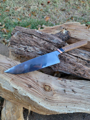 Rhymer Knives | 8 Chef Knives - African Blackwood + Rams Horn with Copper Bolster displayed on a log, showcasing its hand-forged craftsmanship and traditional Japanese hardening technique.