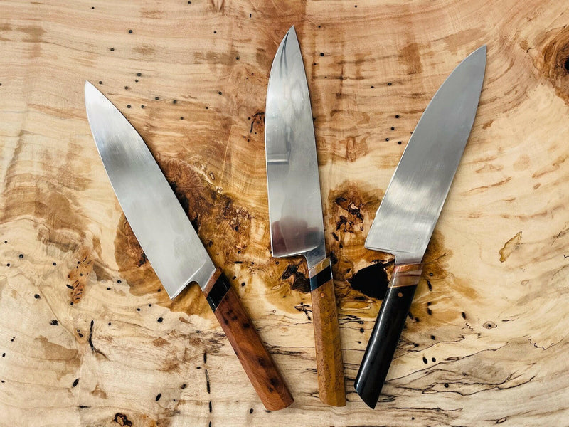Rhymer Knives | 8 Chef Knives - African Blackwood + Rams Horn with Copper Bolster displayed on a wooden surface, showcasing hand-forged craftsmanship and superior handling design.