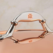 Close-up of Ruffoni Symphonia Cupra 7QT braiser handle and logo, showcasing hammered copper craftsmanship and stainless steel accents for enhanced cooking and presentation.
