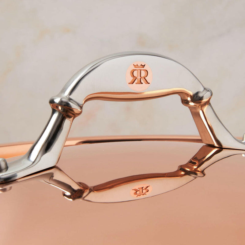 Close-up of Ruffoni Symphonia Cupra 7QT braiser handle and logo, showcasing hammered copper craftsmanship and stainless steel accents for enhanced cooking and presentation.