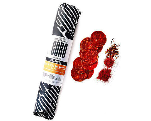 Coro Deli Sticks - Peppercorn - 5 oz displayed with salami slices, pepperoni package, and smoked paprika, highlighting their artisanal flavors and charcuterie suitability.