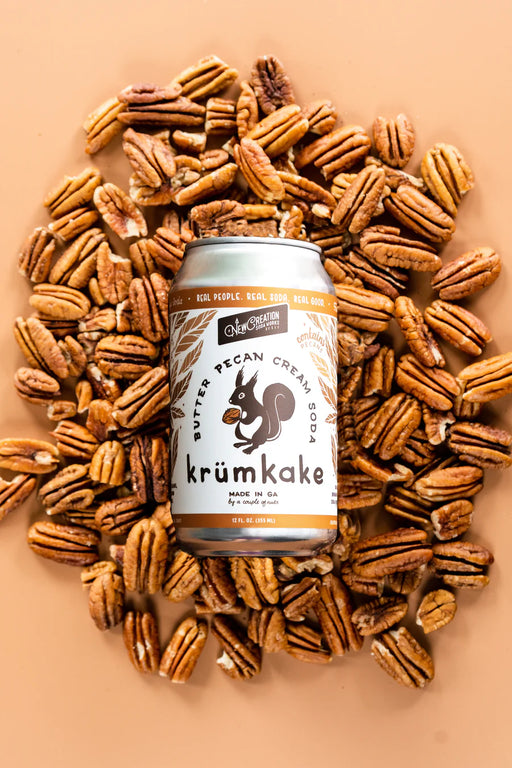 New Creation Soda Works' Krümkake Butter Pecan Cream Soda can, showcased with pecans, embodies creamy, buttery flavors inspired by Swedish pastry.