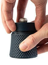 Peugeot Bali Cast Iron Pepper Mill, a small cylindrical device with a textured black base and silver thumbwheel, designed for precise seasoning.