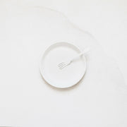 Plain white plate and fork from the Looks Like White ceramics collection by Trudy Crane, showcasing simplicity and organic design, perfect for enhancing dining experiences.