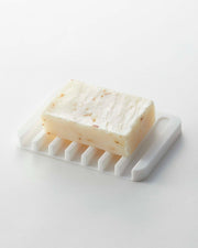 Yamazaki Home | Flow Self-Draining Soap Tray showcasing an oatmeal bar soap on a slotted, water-resistant silicone dish designed to keep counters dry.