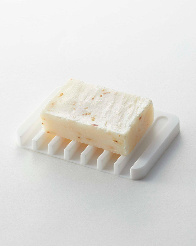 Yamazaki Home | Flow Self-Draining Soap Tray showcasing an oatmeal bar soap on a slotted, water-resistant silicone dish designed to keep counters dry.