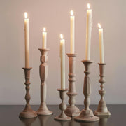 Sir|Madam | Wooden Candlesticks - Tall Georgia No. 3, a hand-carved plantation hardwood candlestick, elegantly displayed among varied silhouettes on a table.